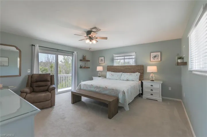 Carpeted bedroom featuring ceiling fan, access to exterior, and multiple windows