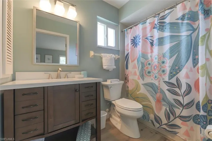Bathroom featuring curtained shower, vanity, toilet, and hardwood / wood-style flooring