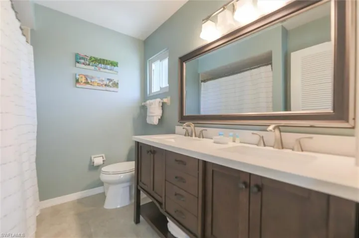 Bathroom with curtained shower, vanity, and toilet