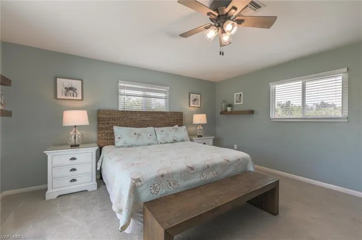 Carpeted bedroom featuring multiple windows and ceiling fan
