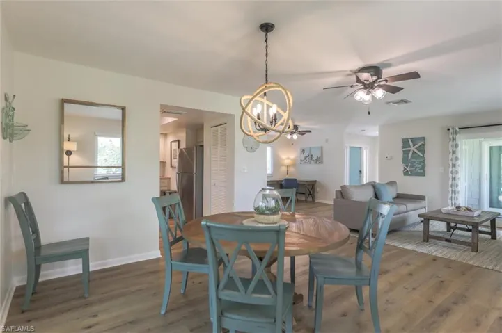 Dining room with ceiling fan with notable chandelier and dark hardwood / wood-style floors