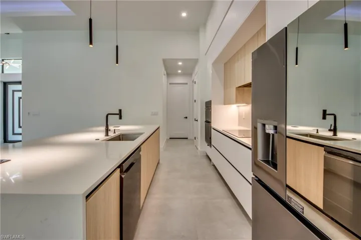 Kitchen with dishwasher, sink, light brown cabinets, and stainless steel fridge