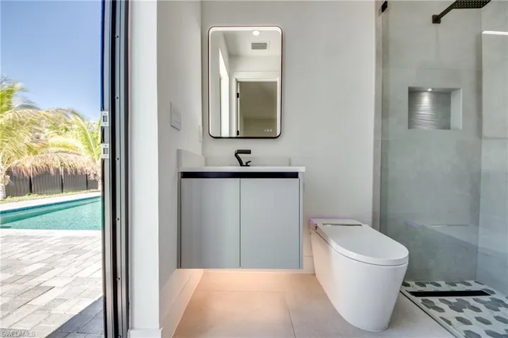Bathroom with tiled shower, toilet, vanity, a wealth of natural light, and tile patterned flooring