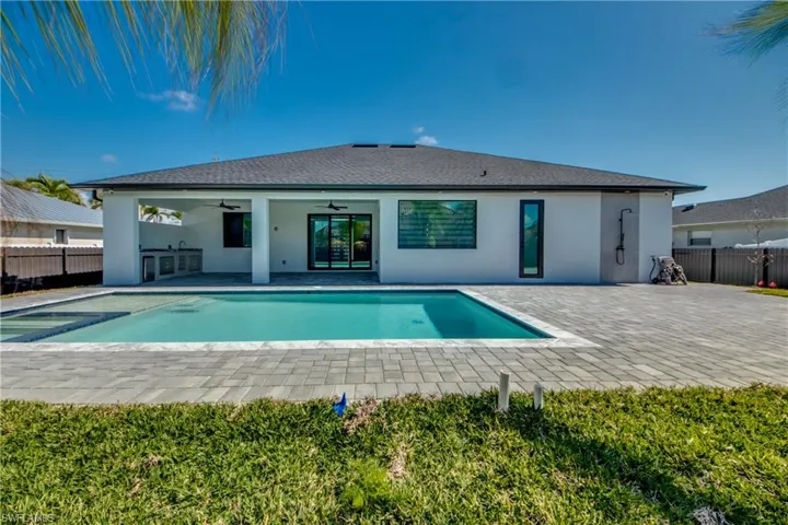 Rear view of property with a fenced in pool, ceiling fan, exterior kitchen, and a patio area