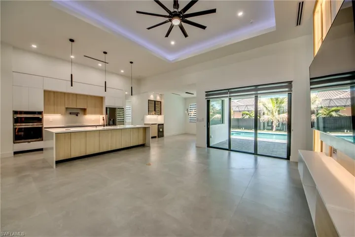 Kitchen featuring white cabinetry, a large island, pendant lighting, and a towering ceiling
