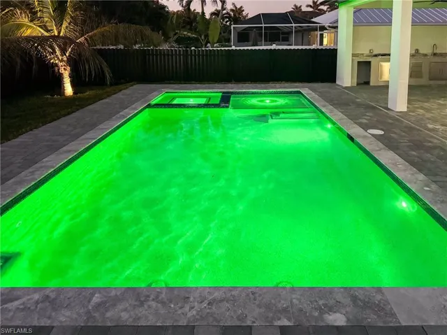 View of swimming pool featuring area for grilling, sink, and a patio area