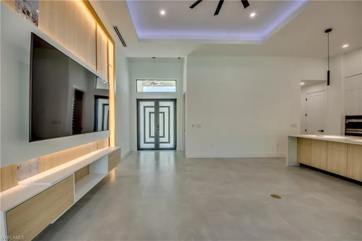 Unfurnished living room with a high ceiling, ceiling fan, and a tray ceiling
