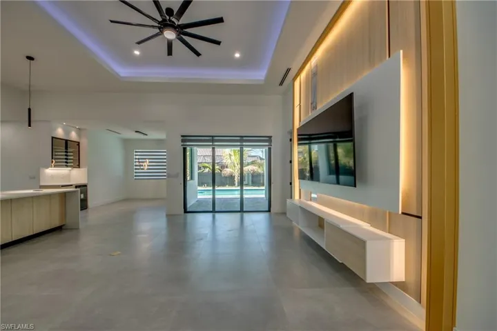 Unfurnished living room featuring ceiling fan and a raised ceiling