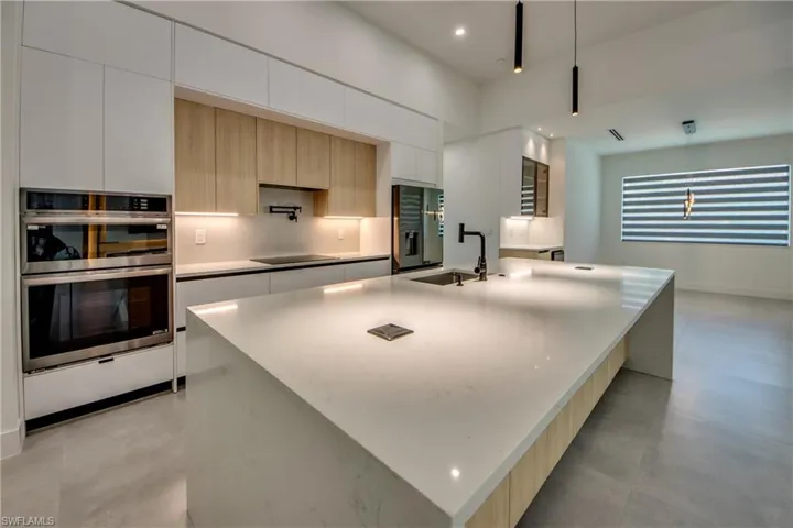 Kitchen with pendant lighting, sink, appliances with stainless steel finishes, a spacious island, and white cabinets