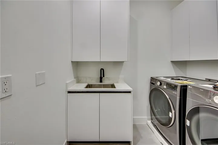 Laundry room with cabinets, washer and clothes dryer, and sink