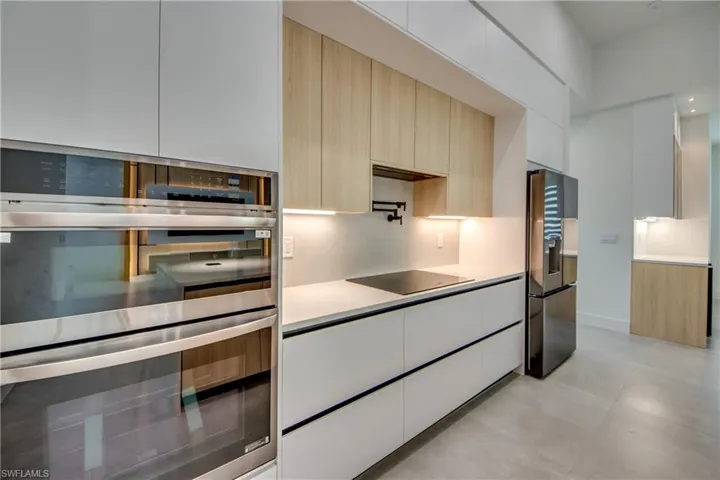 Kitchen with white cabinetry, appliances with stainless steel finishes, backsplash, and light brown cabinetry