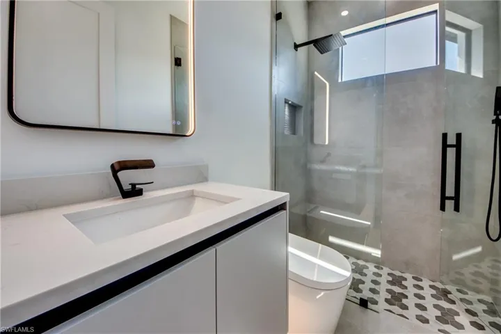 Bathroom featuring vanity, an enclosed shower, and toilet