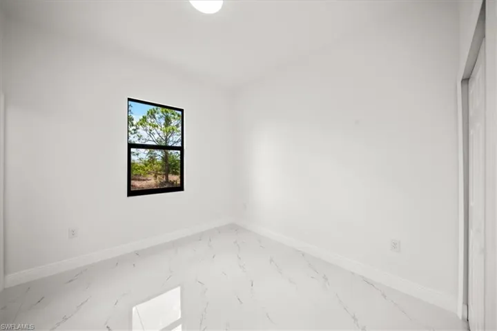 Unfurnished room featuring light marble finish floors and baseboards
