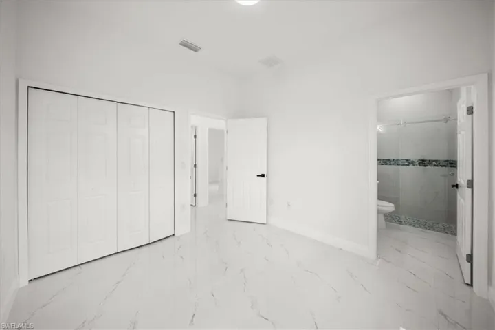 Unfurnished bedroom with marble finish floors, a closet, and connected bathroom