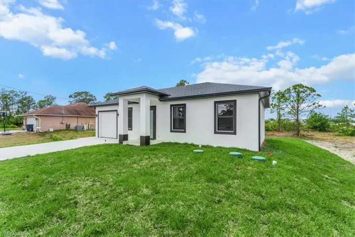 Prairie-style house with a garage, stucco siding, driveway, and a front yard