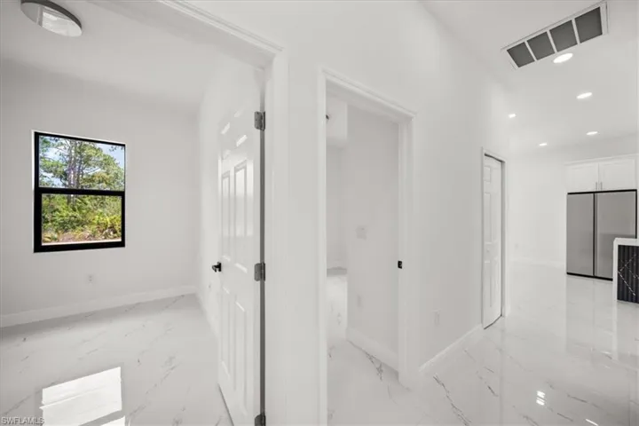 Hallway with light marble finish flooring and recessed lighting