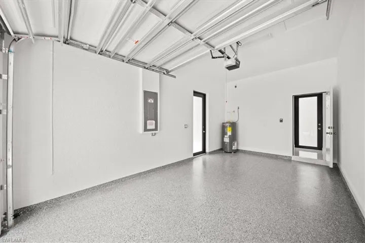 Garage with electric panel, electric water heater, and a garage door opener