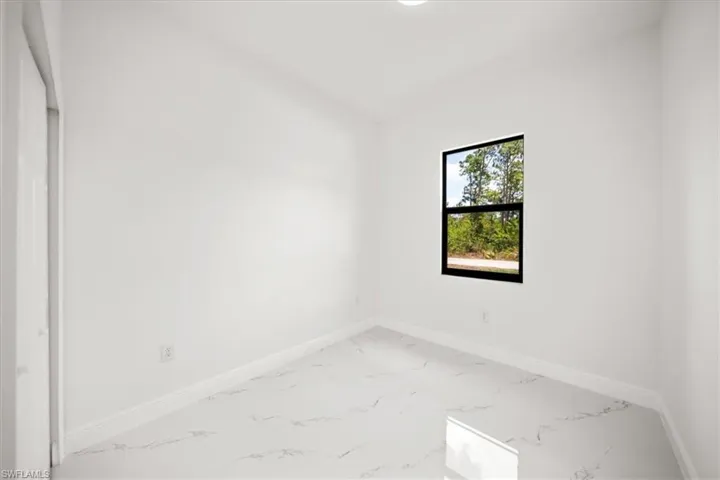 Unfurnished room featuring marble finish floors and baseboards