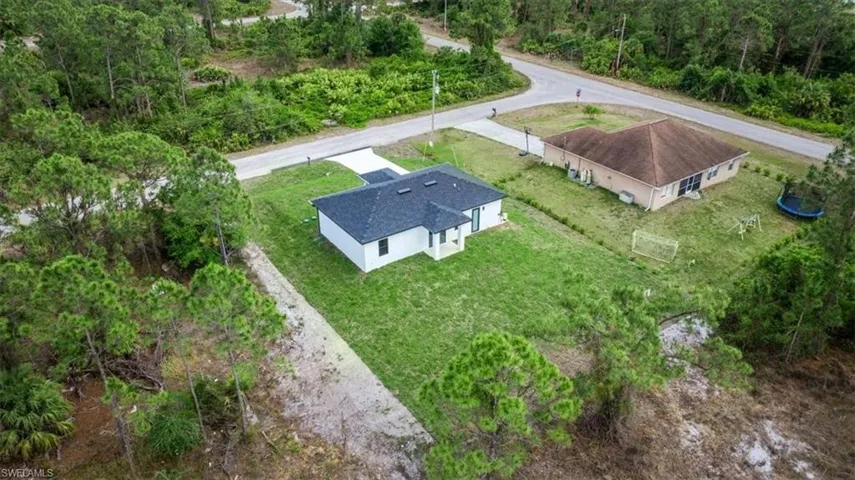 Aerial view of property and surrounding area with a forest