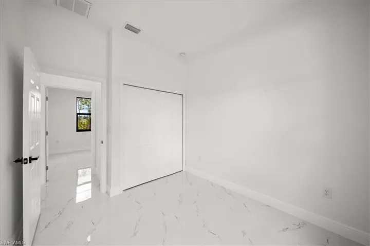 Unfurnished bedroom featuring marble finish flooring and a closet
