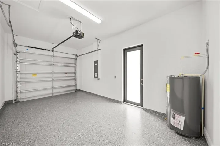 Garage featuring water heater, a garage door opener, and electric panel