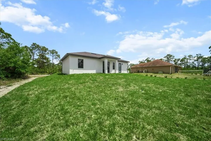 Back of house featuring a yard and stucco siding