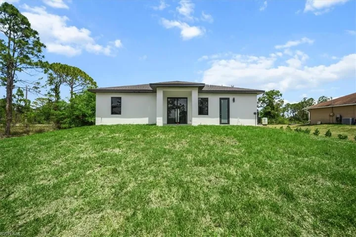 Back of house with stucco siding and a yard
