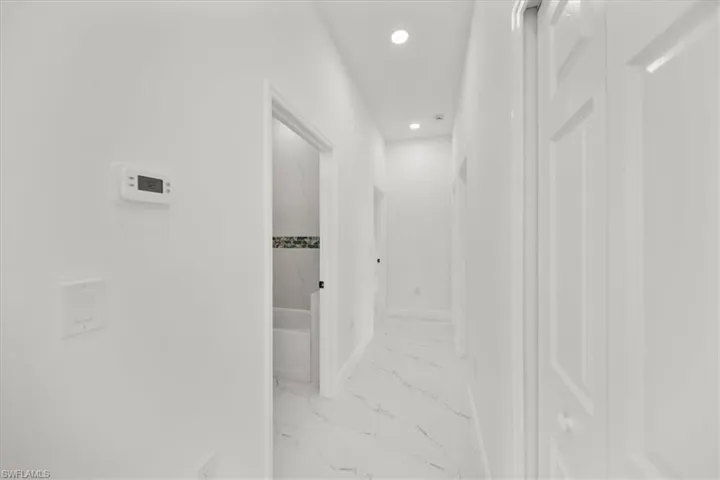 Corridor with light marble finish floors and recessed lighting