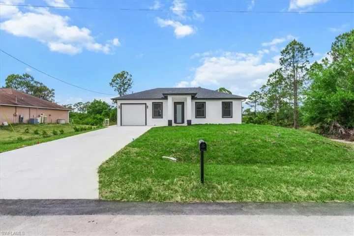 Prairie-style home featuring driveway, an attached garage, stucco siding, and a front lawn