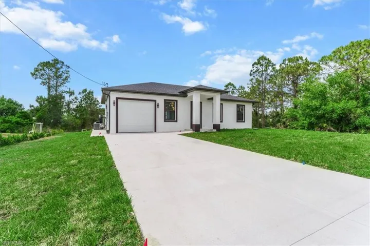 Prairie-style house featuring a garage, stucco siding, a front lawn, and concrete driveway