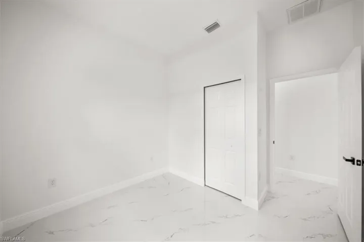 Unfurnished bedroom with marble finish flooring and a closet