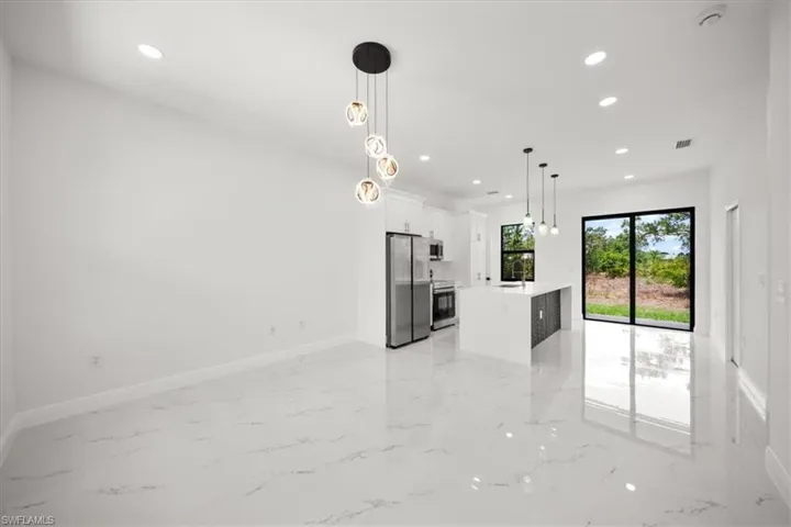 Kitchen with light marble finish flooring, freestanding refrigerator, recessed lighting, light countertops, and white cabinetry