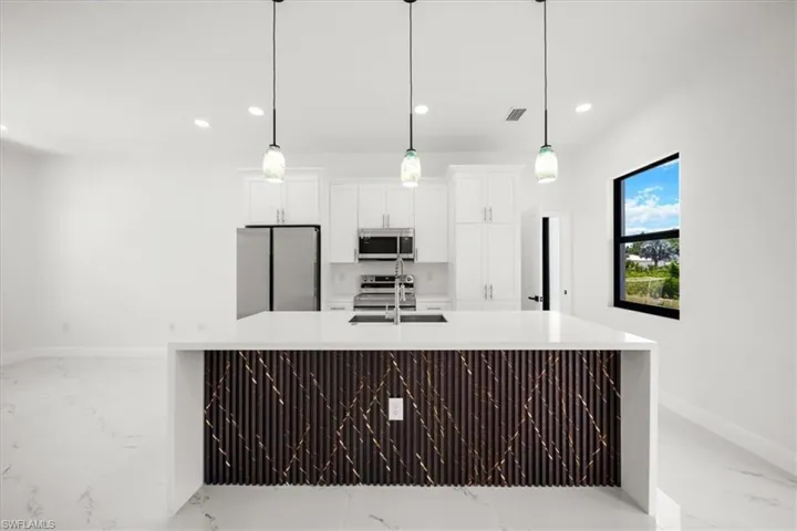Kitchen featuring light marble finish flooring, light countertops, stainless steel appliances, recessed lighting, and white cabinets