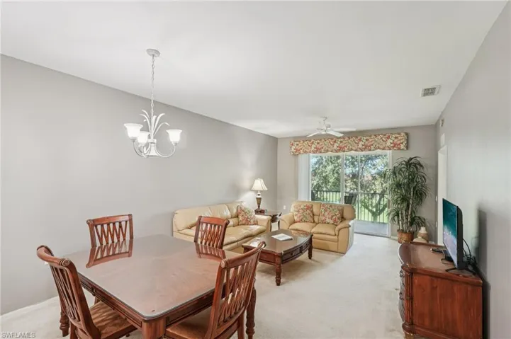 Dining room featuring light colored carpet, ceiling fan, and a chandelier