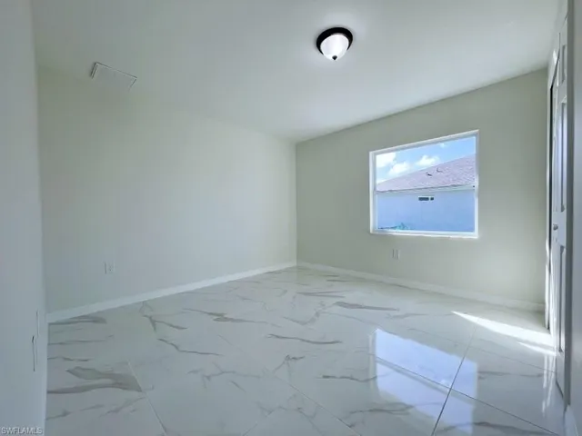 Spare room featuring baseboards and light marble finish floors
