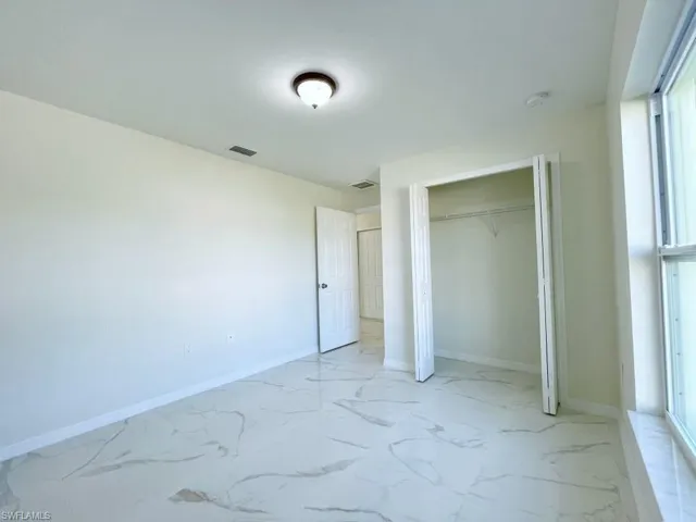 Unfurnished bedroom featuring light marble finish flooring and a closet