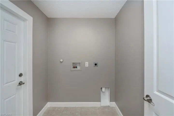 Clothes washing area featuring hookup for an electric dryer, hookup for a gas dryer, hookup for a washing machine, and light tile patterned floors