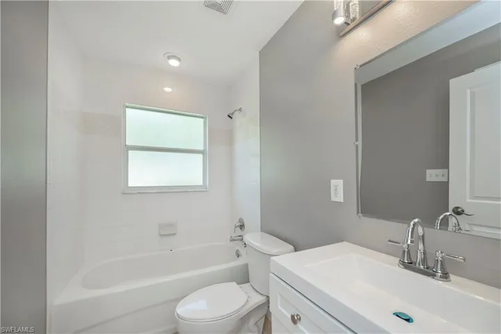 Full bathroom featuring vanity, tiled shower / bath combo, and toilet