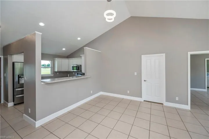 Kitchen with stainless steel appliances, high vaulted ceiling, and light tile patterned floors