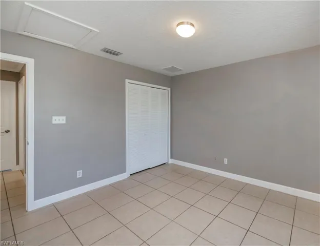 Unfurnished bedroom featuring light tile patterned flooring and a closet