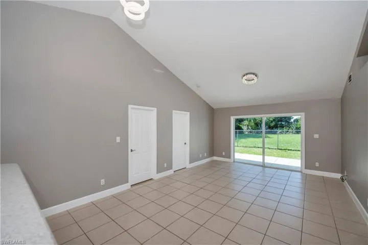 Unfurnished room featuring light tile patterned floors and high vaulted ceiling