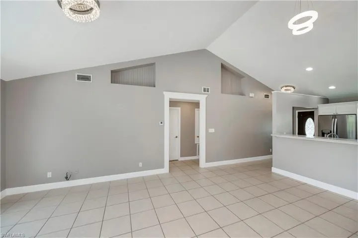 Empty room featuring light tile patterned floors and lofted ceiling