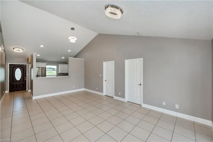 Unfurnished living room with light tile patterned flooring, high vaulted ceiling, and a textured ceiling
