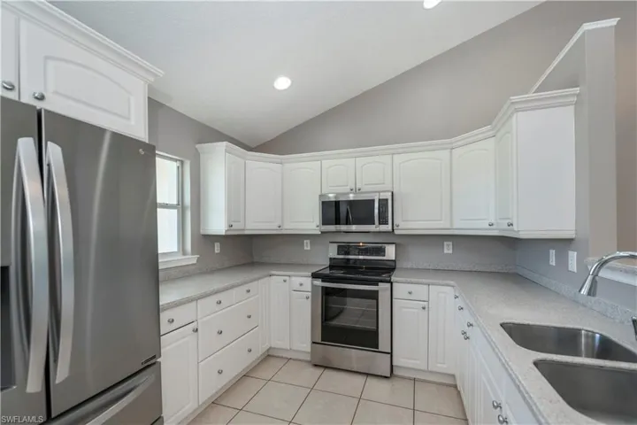 Kitchen featuring sink, light tile patterned floors, white cabinetry, and stainless steel appliances
