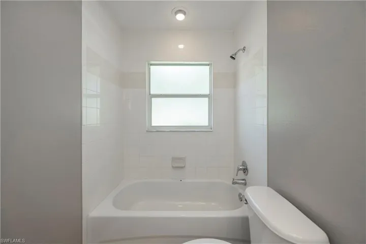 Bathroom with tiled shower / bath combo and toilet