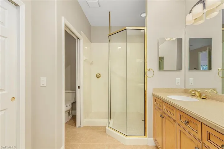 Bathroom with vanity, tile patterned flooring, toilet, and a shower with door