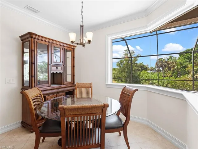 Breakfast nook with light tile patterned floors, visible vents, an inviting chandelier, ornamental molding, and baseboards