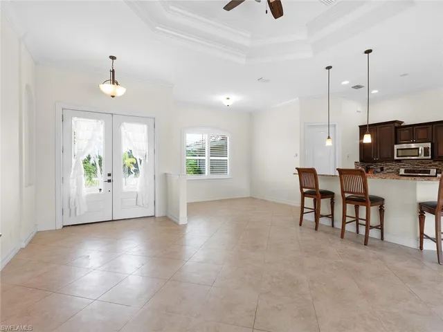 Foyer with a tray ceiling, ornamental molding, and french doors