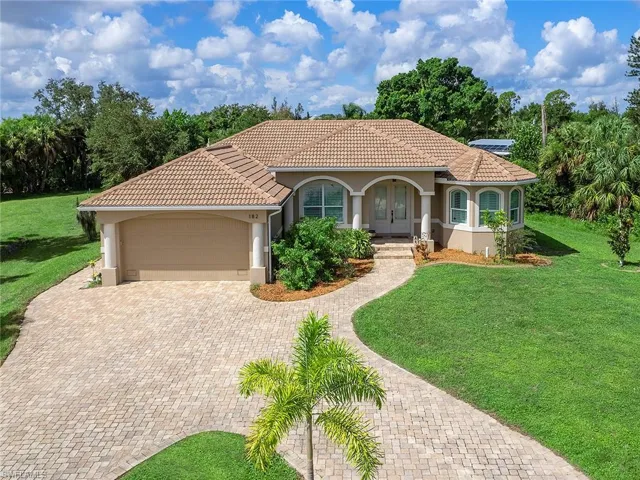 Mediterranean / spanish-style home featuring decorative driveway, a tiled roof, a front lawn, and stucco siding
