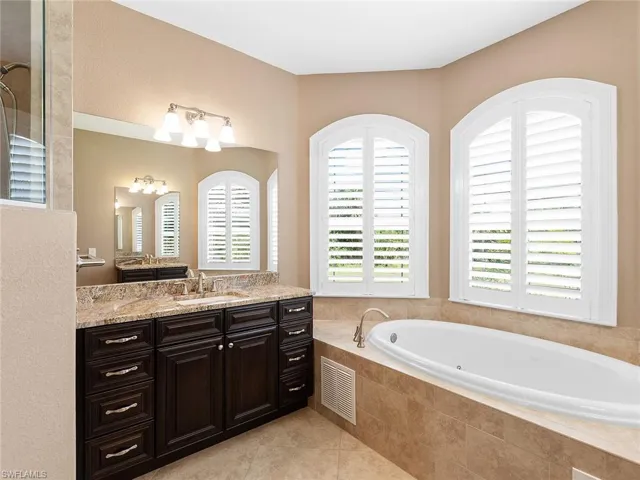 Bathroom featuring tile patterned flooring, visible vents, vanity, and a bath